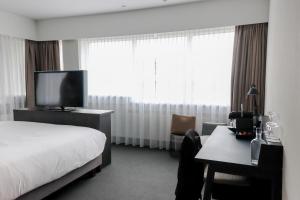 a hotel room with a bed, desk and television at Mercure Hotel Tilburg Centrum in Tilburg