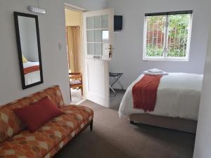 a bedroom with a bed and a couch and a window at 6 on Kloof Guest House in Bredasdorp