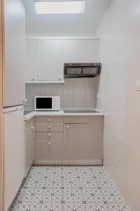 uma cozinha com armários brancos e um micro-ondas em Apartamento Marina Suite em Benalmádena