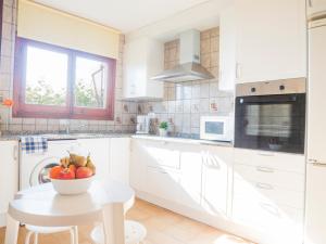 a white kitchen with a bowl of fruit on a table at Casas Pareadas Romana in Alcossebre +22 photos
