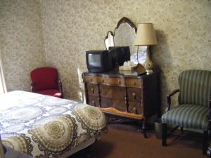 a bedroom with a bed and a dresser with a tv on it at Auberge des Arts Bed and Breakfast in Ottawa