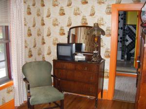 a room with a chair, desk and a television at Auberge des Arts Bed and Breakfast in Ottawa