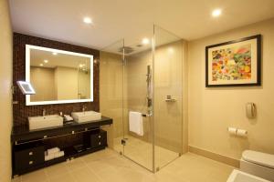 a bathroom with a shower and a sink and a mirror at The Oterra in Bangalore