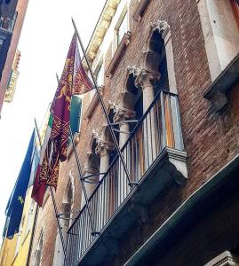 two flags on a balcony on a building at Hotel Palace Bonvecchiati in Venice