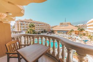 a balcony with a table and chairs and a pool at Hotel Cleopatra Palace in Playa de las Americas