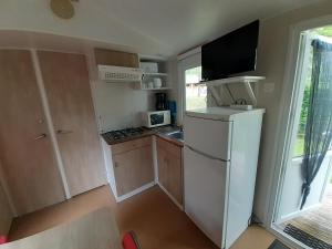 a small kitchen with a refrigerator and a microwave at Camping Municipal La Prade in Sorgeat