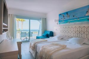 two beds in a hotel room with a view of the ocean at Iberostar Waves Royal Andalus in Chiclana de la Frontera