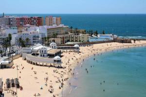 un gruppo di persone su una spiaggia vicino all'oceano di Apartamento Oh Cádiz a Cadice
