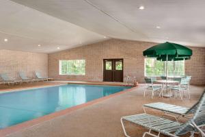 a swimming pool with chairs and a table and an umbrella at Days Inn by Wyndham Whitmore Lake in Whitmore Lake