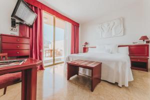 a bedroom with a bed and a tv and a table at Hotel Cleopatra Palace in Playa de las Americas