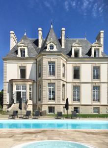 une grande maison avec une piscine en face de celle-ci dans l'établissement Les Garennes - Hôtel Spa Bénodet, à Bénodet