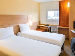 a hotel room with two beds and a desk at ibis Leeds Centre Marlborough Street in Leeds