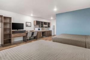 Habitación con 2 camas y escritorio con TV. en WoodSpring Suites North Ft Worth Alliance TX Speedway en Fort Worth