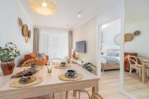 a dining room and living room with a table and chairs at BellMi Apartamenty Kasprowicza 20 in Kołobrzeg