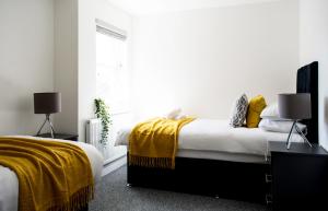 a bedroom with two beds with yellow blankets and a window at 2 Bedroom Apartment Leamington Spa Hosted By Golden Key in Lillington