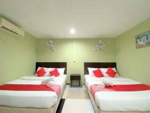 two beds in a room with red and white pillows at OYO 873 Bamboo Inn in Batu Ferringhi