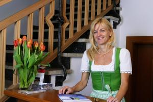 a woman standing at a table with a vase of tulips at Gästehaus Hochmuth in Mayrhofen
