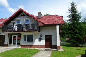 a house with a red roof and a balcony at Apartamenty BB nad Kryniczanką in Krynica Zdrój