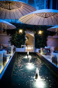 - une piscine dans un hôtel avec des parasols dans l'établissement Auberge De Saint-Rémy - Hôtel - Restaurant Gastronomique Étoilé - Saint Rémy de Provence, à Saint-Rémy-de-Provence