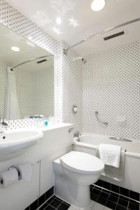 a white toilet sitting next to a bath tub in a bathroom at Holiday Inn London Brent Cross, an IHG Hotel in London