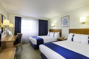 a hotel room with two beds and a desk at Holiday Inn London Brent Cross, an IHG Hotel in London