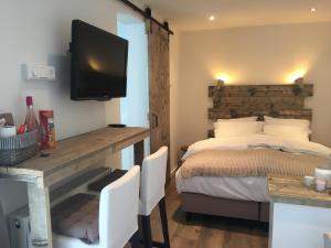 1 dormitorio con 1 cama y escritorio con TV en Romana, en Zandvoort