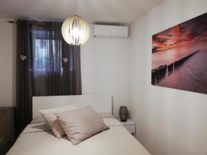 ein Schlafzimmer mit einem weißen Bett und einem Gemälde an der Wand in der Unterkunft Studio Apartman Lenka in Split