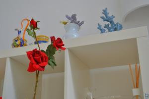a white shelf with red roses and vases on it at B&b Mondello Resort in Palermo