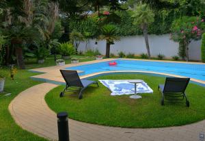 two chairs and a table next to a swimming pool at B&b Mondello Resort in Palermo