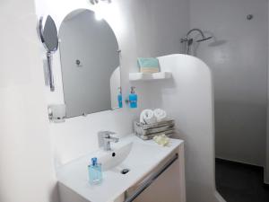 bagno bianco con lavandino e specchio di Tasoula Guest House ad Adámas