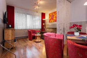 a living room with a table and red chairs at H&H Apartments im Herzen der Stadt teilweise mit Balkon ruhig zentral modern mit Küche in Greifswald