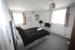 um quarto com uma cama, uma televisão e janelas em Holden Court Apartment - Apt 1 em West Drayton