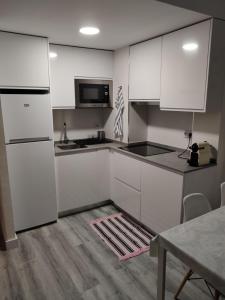 uma cozinha branca com armários brancos e uma mesa em Apartamento Mare Nostrum Playa Arrabassada em Tarragona