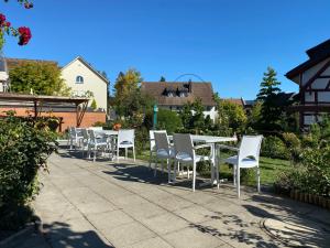 シュタイン・アム・ラインにあるGarni-Hotel Mühletalの白いテーブルと椅子が並ぶパティオ