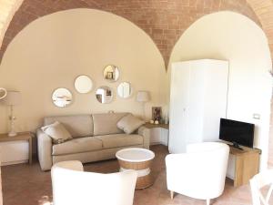 a living room with a couch and white chairs at La Solina in Bibbona
