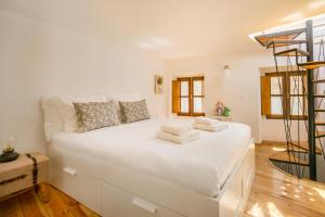 a large white bed in a room with wooden floors at Casa da Pedra - Monsanto in Monsanto