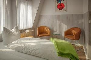 um quarto com uma cama e duas cadeiras em H&H Apartments im Herzen der Stadt in der Lange Strasse geräumig ruhig mit Küche und Esstisch em Greifswald