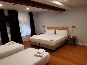 リャネスにあるHotel Puerto de Llanesのベッド2台、テーブル(ランプ2つ付)が備わる客室です。