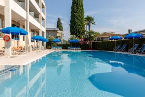 a large swimming pool with blue umbrellas and chairs at Hotel Idania in Bardolino
