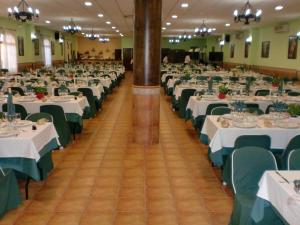 un gran salón de banquetes con mesas blancas y sillas verdes en Hostal las Tres Jotas, en Alcaracejos