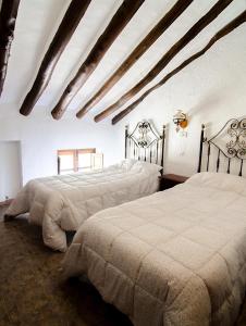1 dormitorio con 2 camas y techo con vigas. en Cortijo Alzamigaja en Archidona
