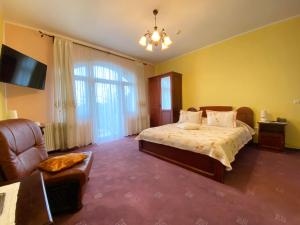1 dormitorio con cama, sofá y TV en Pensiunea Crocus - Sauna & Billiard en Poiana Brasov