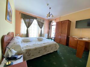 a bedroom with a large bed and a television at Pensiunea Crocus - Sauna & Billiard in Poiana Brasov