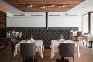 una sala da pranzo con tavoli e sedie bianchi di Hotel Gasthof Jochele a Falzes