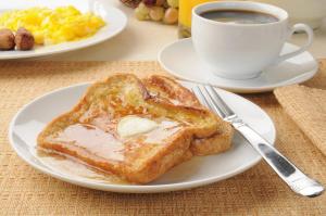a plate of toast with butter and a cup of coffee at Hotel Boutique Lacoul Inn in Bhairāhawā
