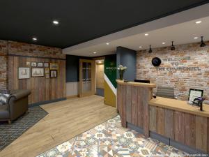 a lobby with a reception desk and a brick wall at The Churchill By Greene King Inns in Royal Wootton Bassett