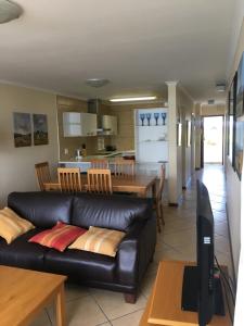 sala de estar con sofá de cuero negro y cocina en Laguna Grove 50 3 bedroom, en Knysna