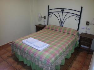 a bedroom with a bed with a plaid blanket and two tables at Hostal las Tres Jotas in Alcaracejos
