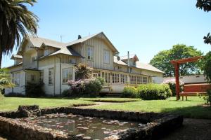 a house with a koi pond in front of it at Playa Maqui Lodge in Frutillar