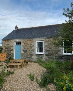 a brick cottage with a blue door and a bench at The Old Sunday School in Helston